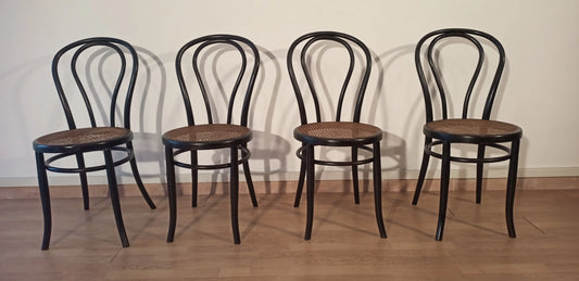 Quatre chaises de salle à manger en hêtre courbé noir, de style Thonet Italia, disposées en rangée.