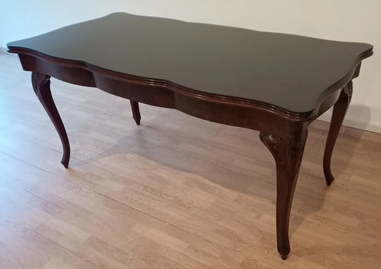 Magnifique table Chippendale vintage en verre trempé fumé, pieds galbés et bords festonnés, en bois foncé.