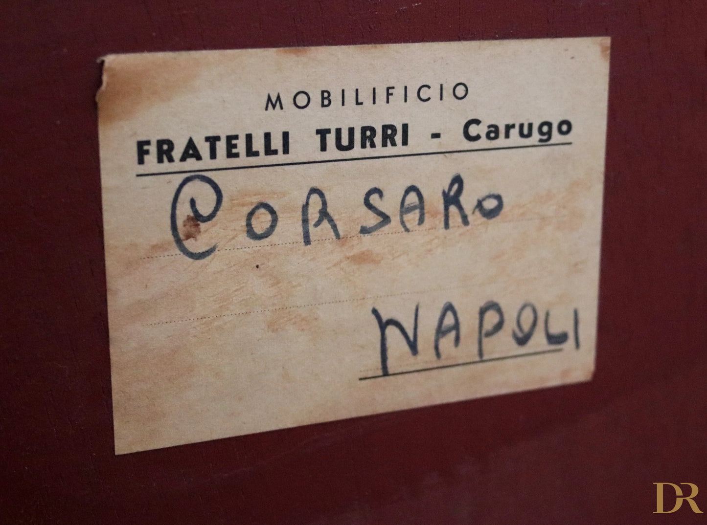 Etichetta in carta consumata con testo stampato e manoscritto sul retro di credenza di osvaldo borsani in mogano e onice