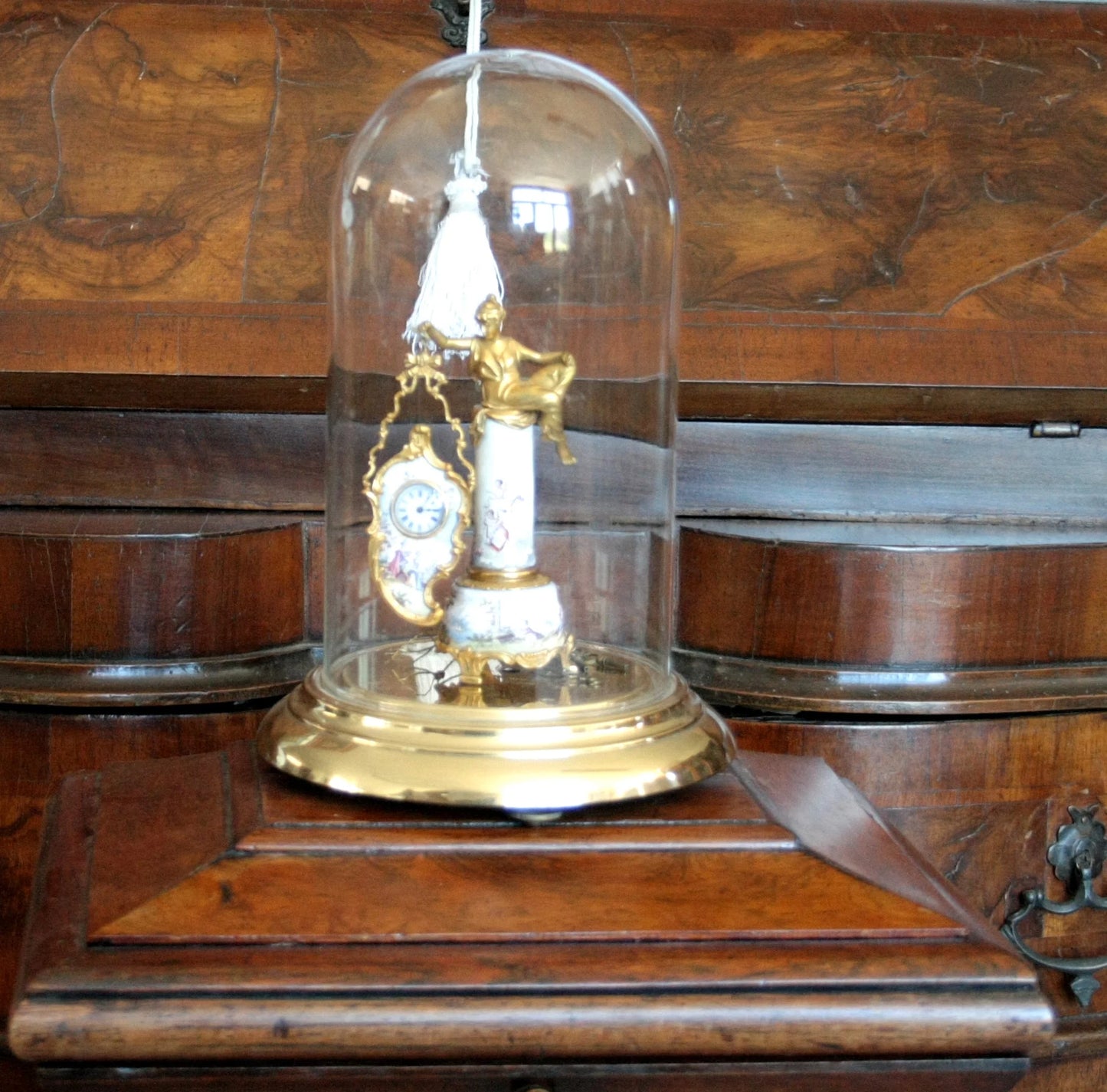 Pendule de table Art Déco en bronze et émail, ornée d'une figure féminine et d'une scène galante, sur un socle du XIXe siècle sous cloche de verre.