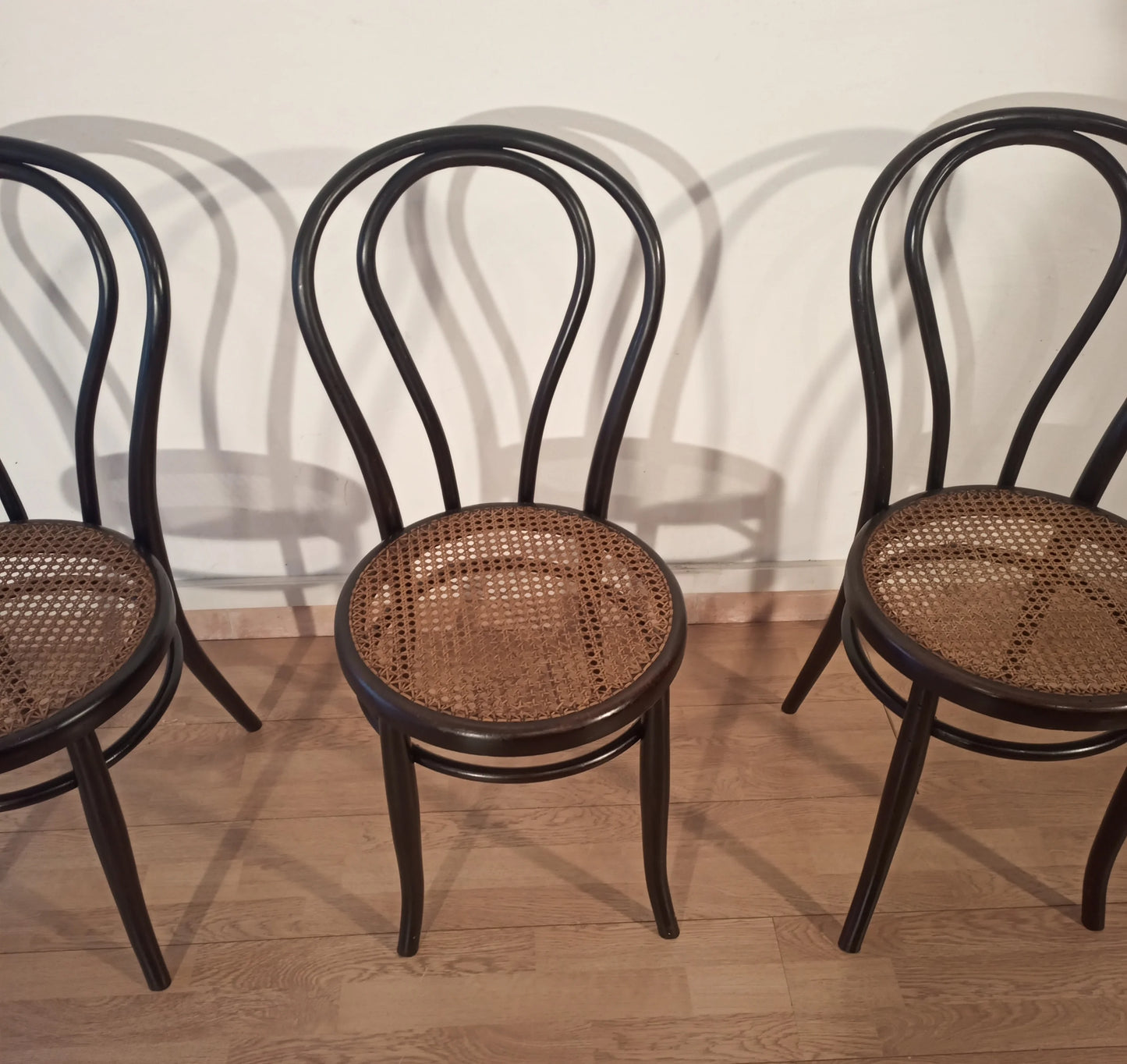 Tre sedie nere in faggio curvato con sedili in vimini nello stile thonet italia set, disposte in fila